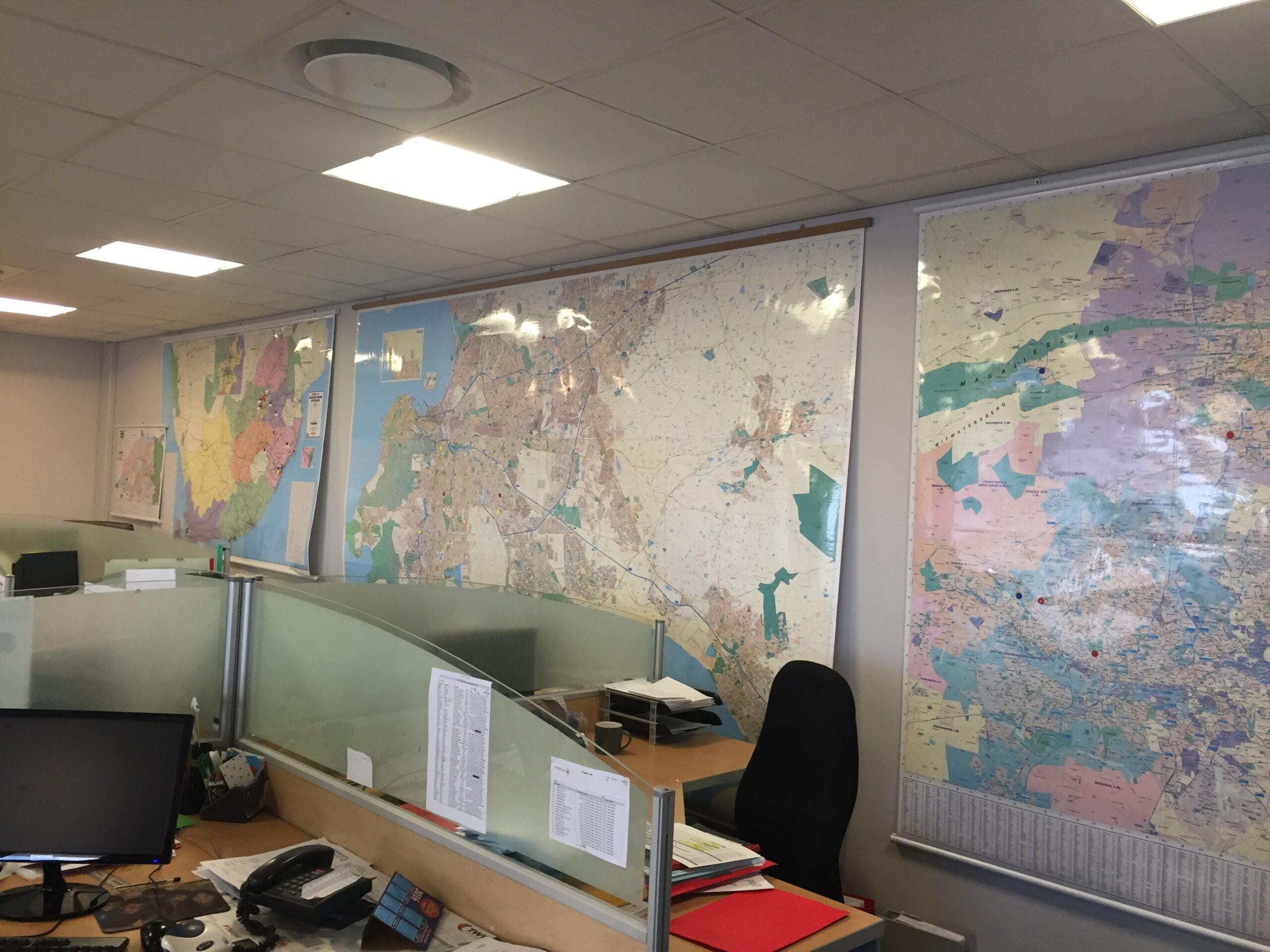 Office with maps on the wall and a desk with computer equipment.